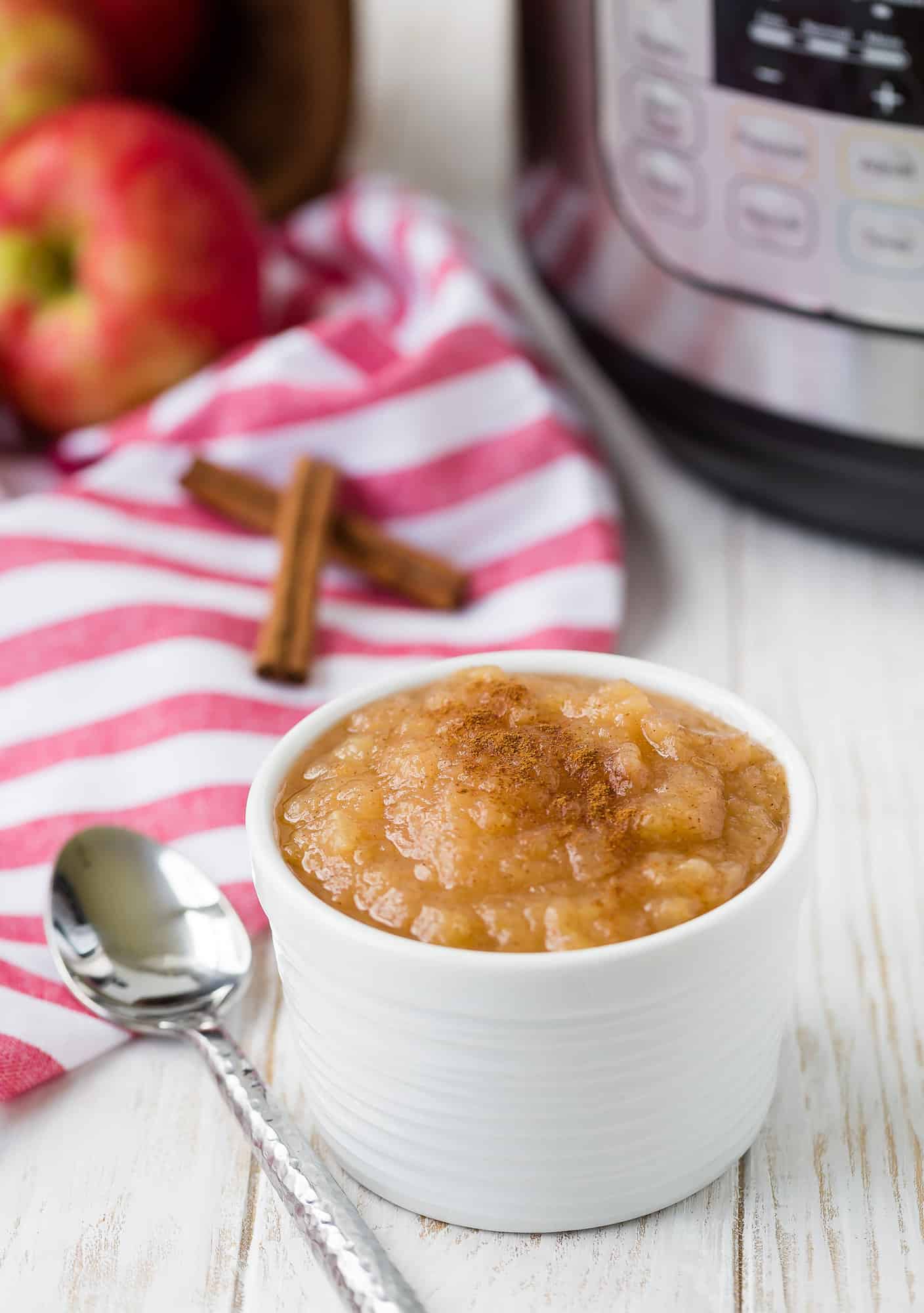 Applesauce in a small bowl, pressure cooker in background.