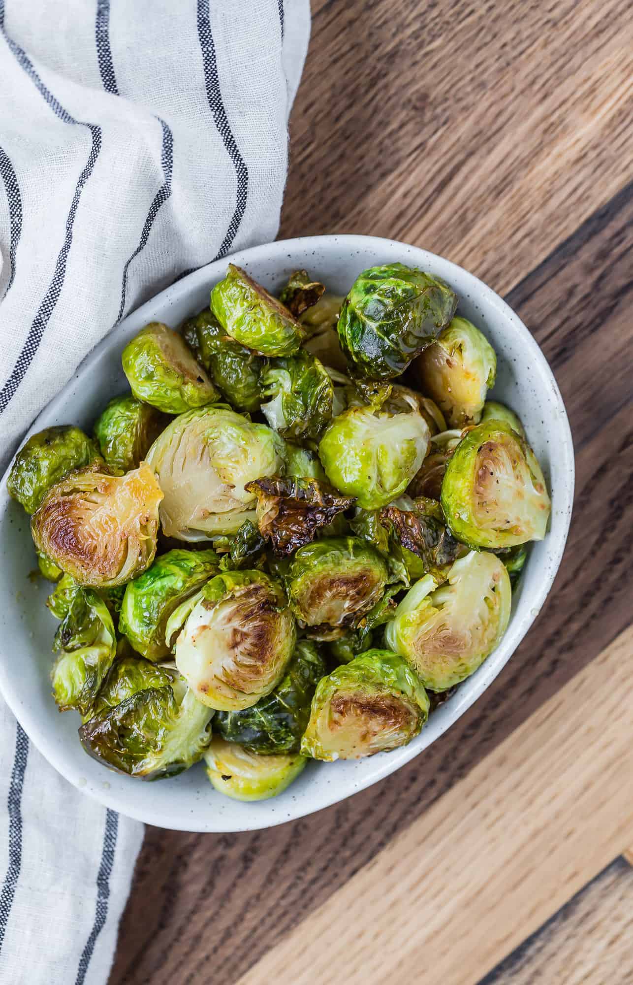 Brussels sprouts in a bowl, wooden backdrop.