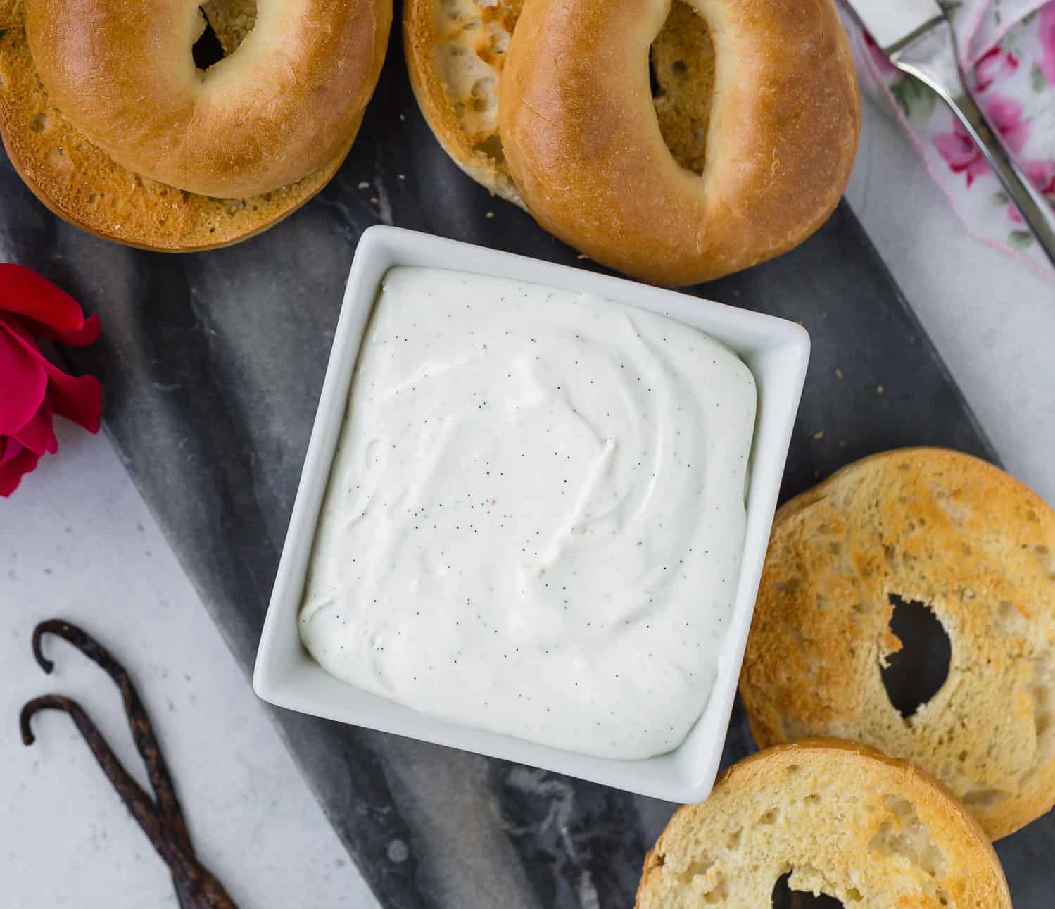 Cream cheese in a dish surrounded by bagels.