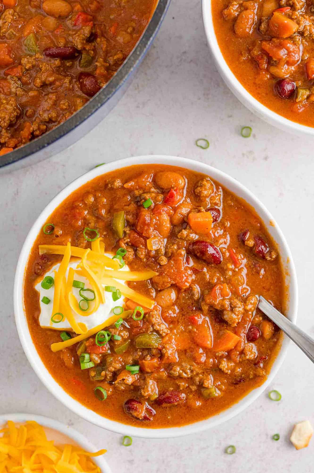 Beef chili with beans, with toppings and a spoon.