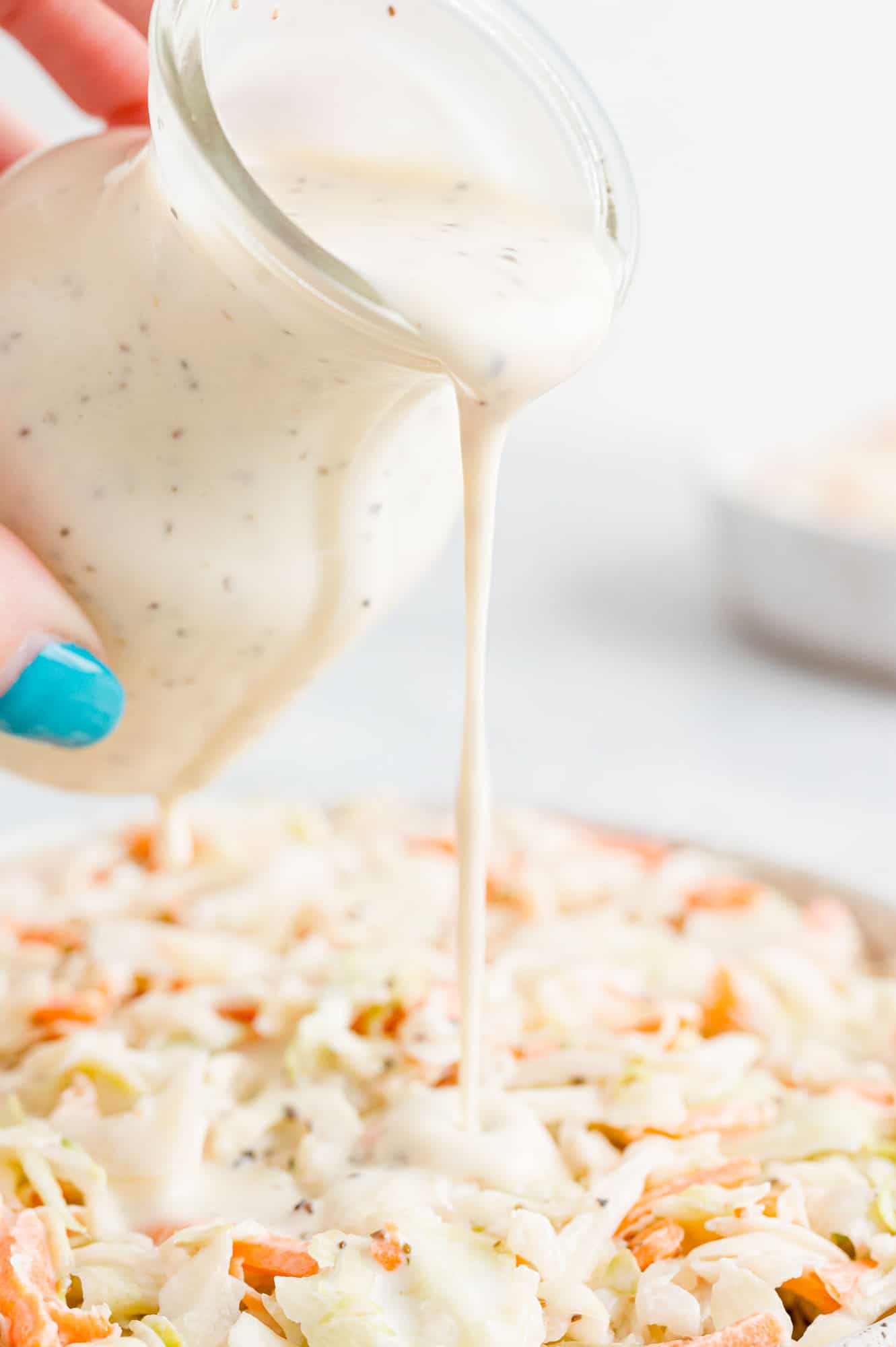 Dressing being poured onto coleslaw.