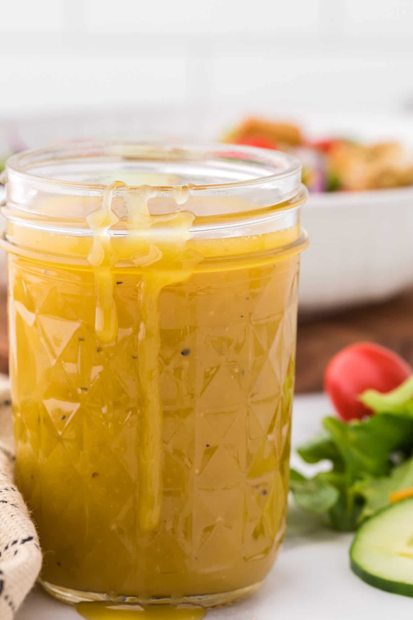Honey mustard vinaigrette dressing dripping down side of jar.