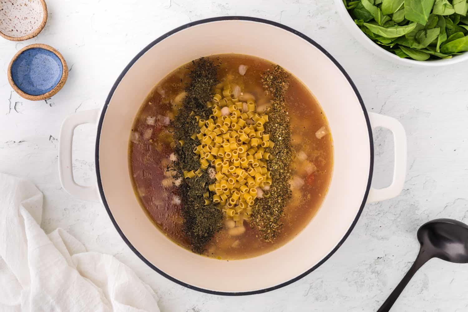 Broth, beans, and herbs added to pan.