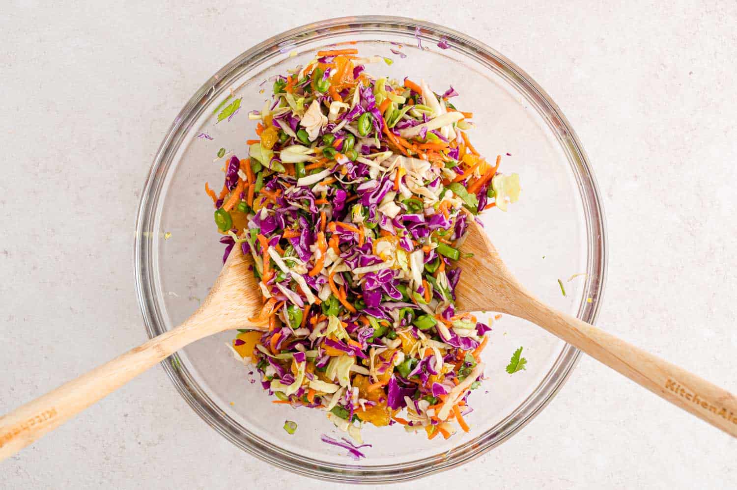 Cabbage salad being mixed with two spoons.