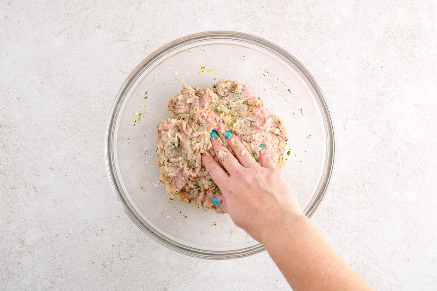 Ingredients for burgers mixed together in glass bowl.