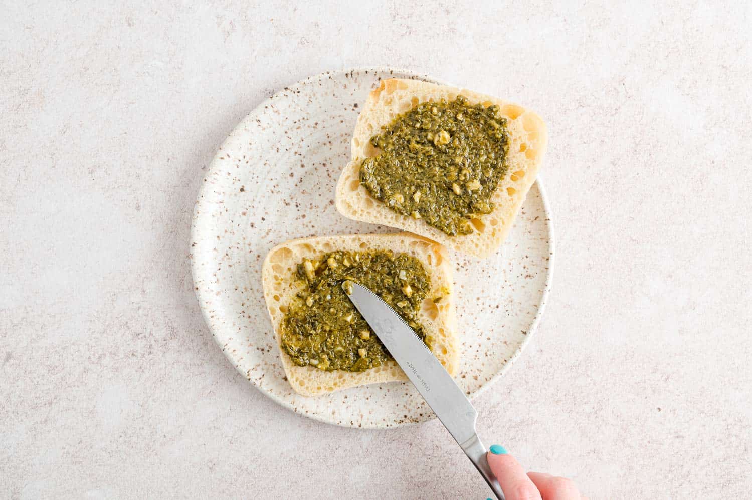 Pesto being spread on a bun.