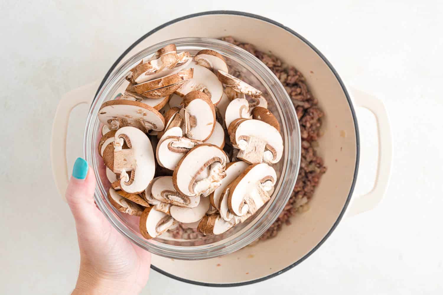 Mushrooms being added to pan.