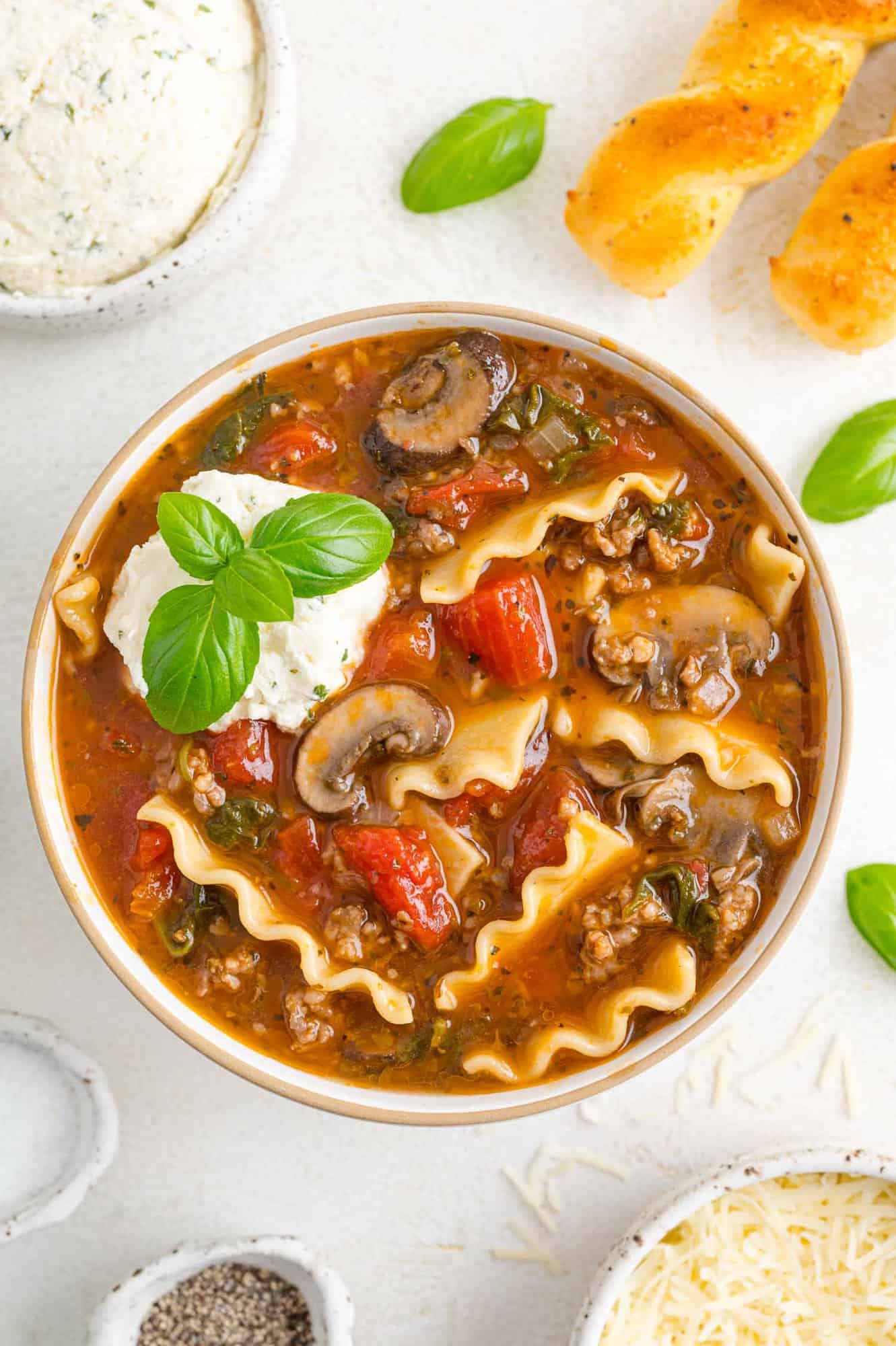 Lasagna soup in a bowl with cheese topping.