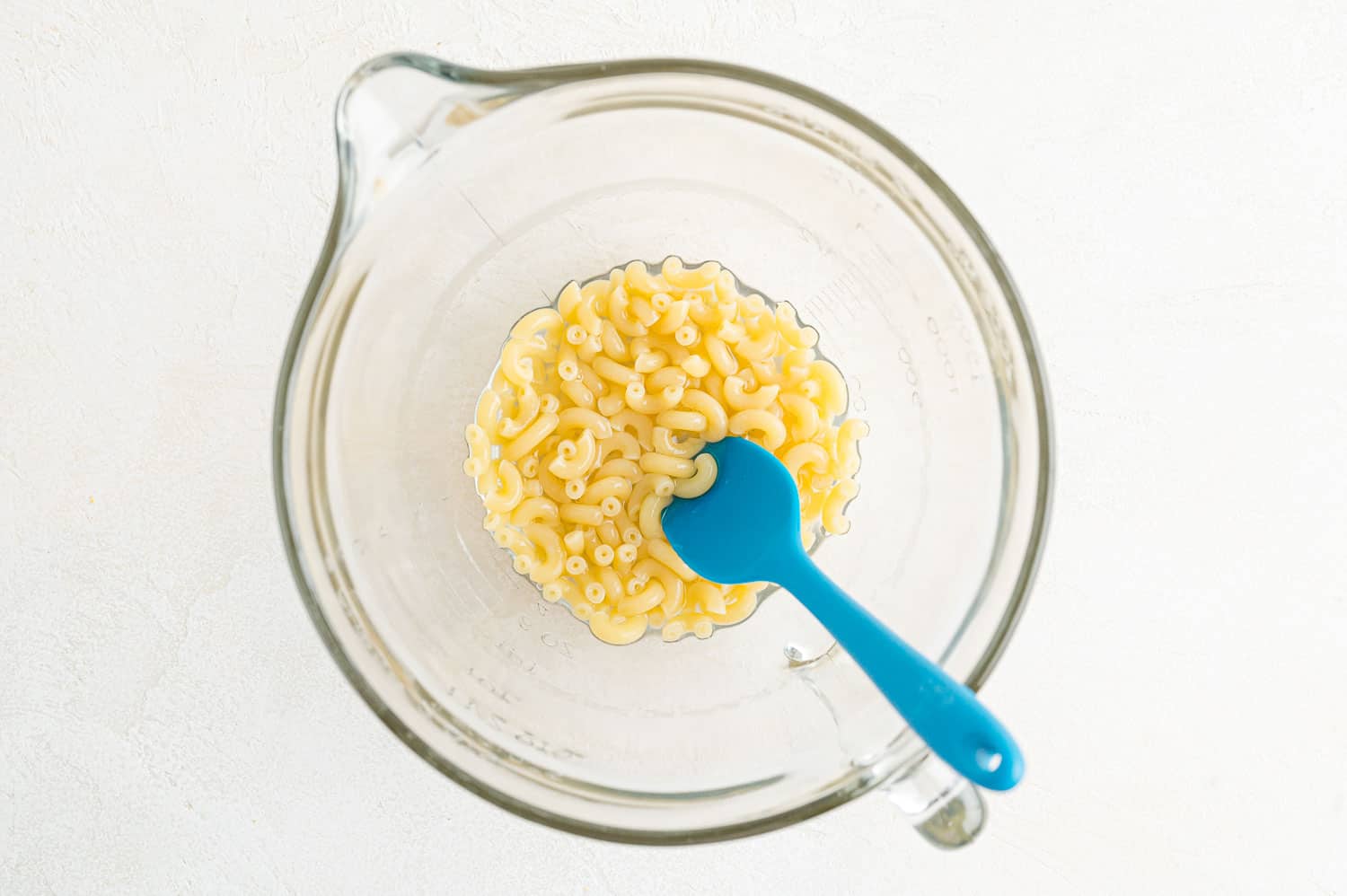 Macaroni pasta in a large bowl, mostly cooked.