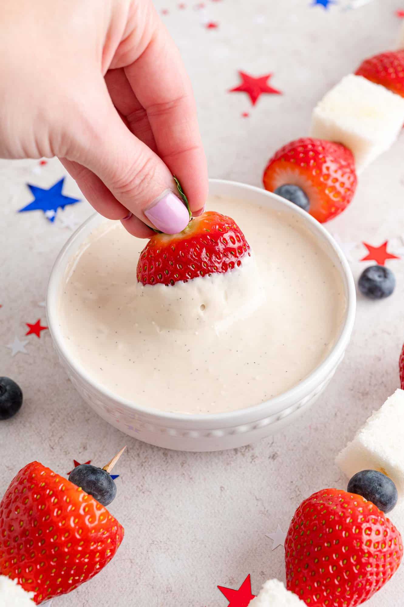 Strawberry being dipped in yogurt dip.