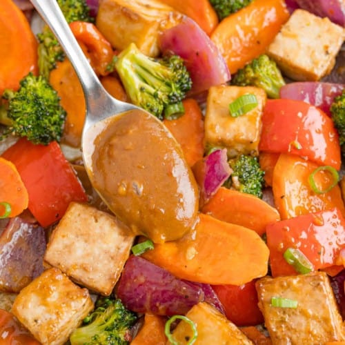 Peanut sauce being added to tofu sheet pan dinner.