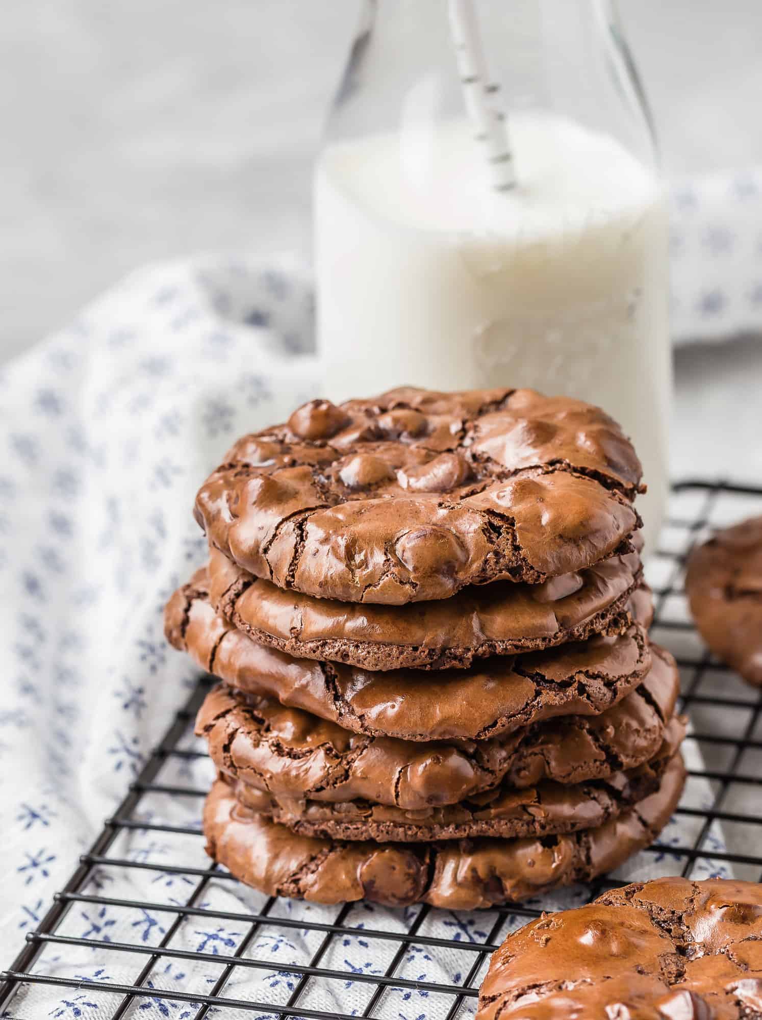 Stack of chocolate cookies, milk in background.