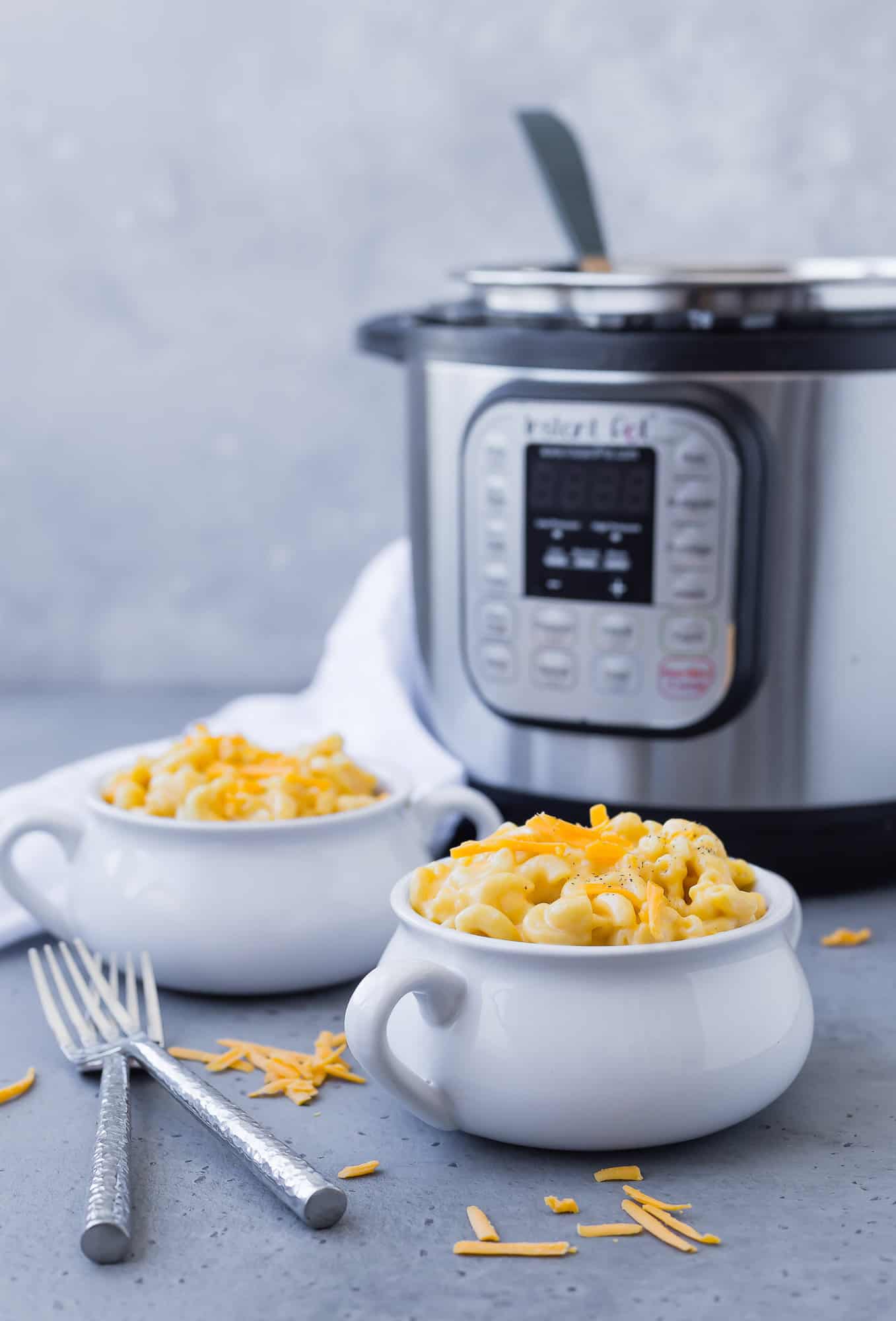 Macaroni and cheese in two bowls, instant pot in background.