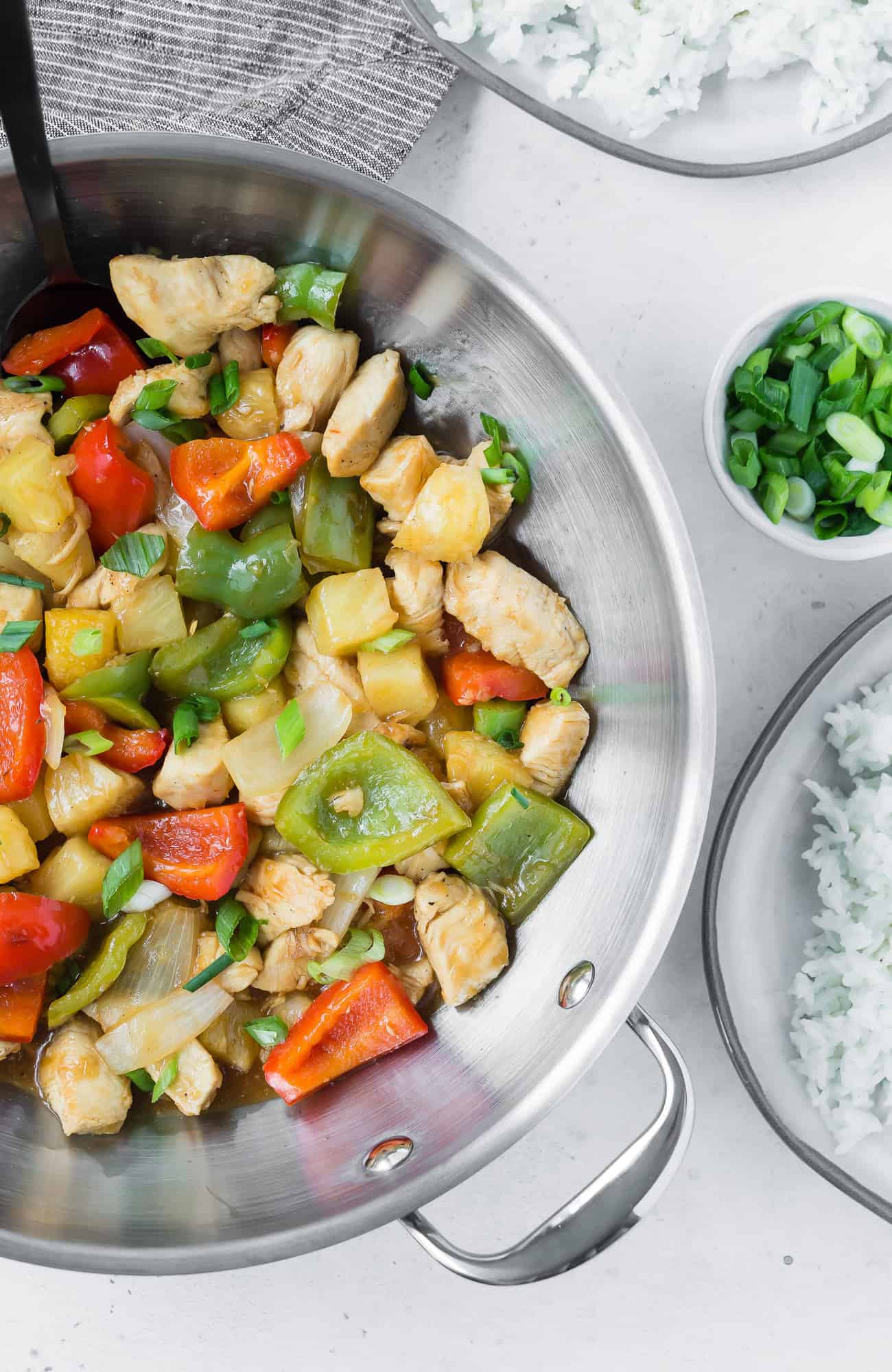 Chicken stir fry in a wok with peppers and pineapple.