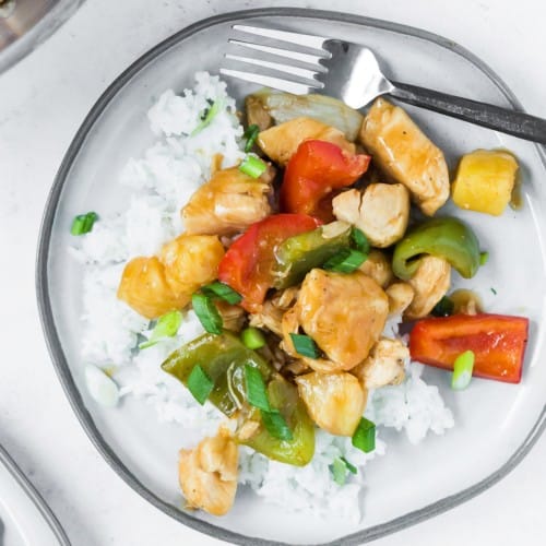 Sweet and sour chicken stir fry on a plate with rice.