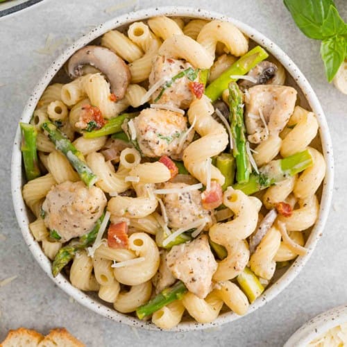 Chicken and asparagus pasta in white bowl.