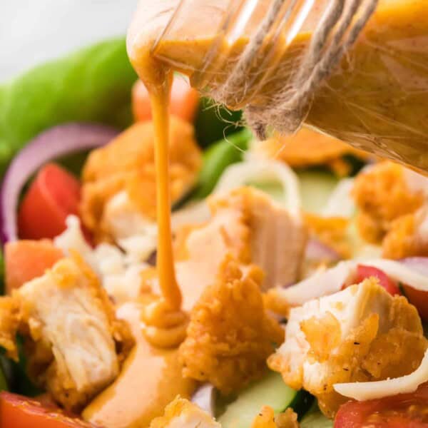 Honey mustard dressing being poured on a salad.
