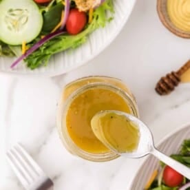 Honey mustard vinaigrette with a spoon.