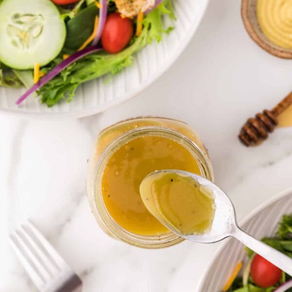 Honey mustard vinaigrette with a spoon.