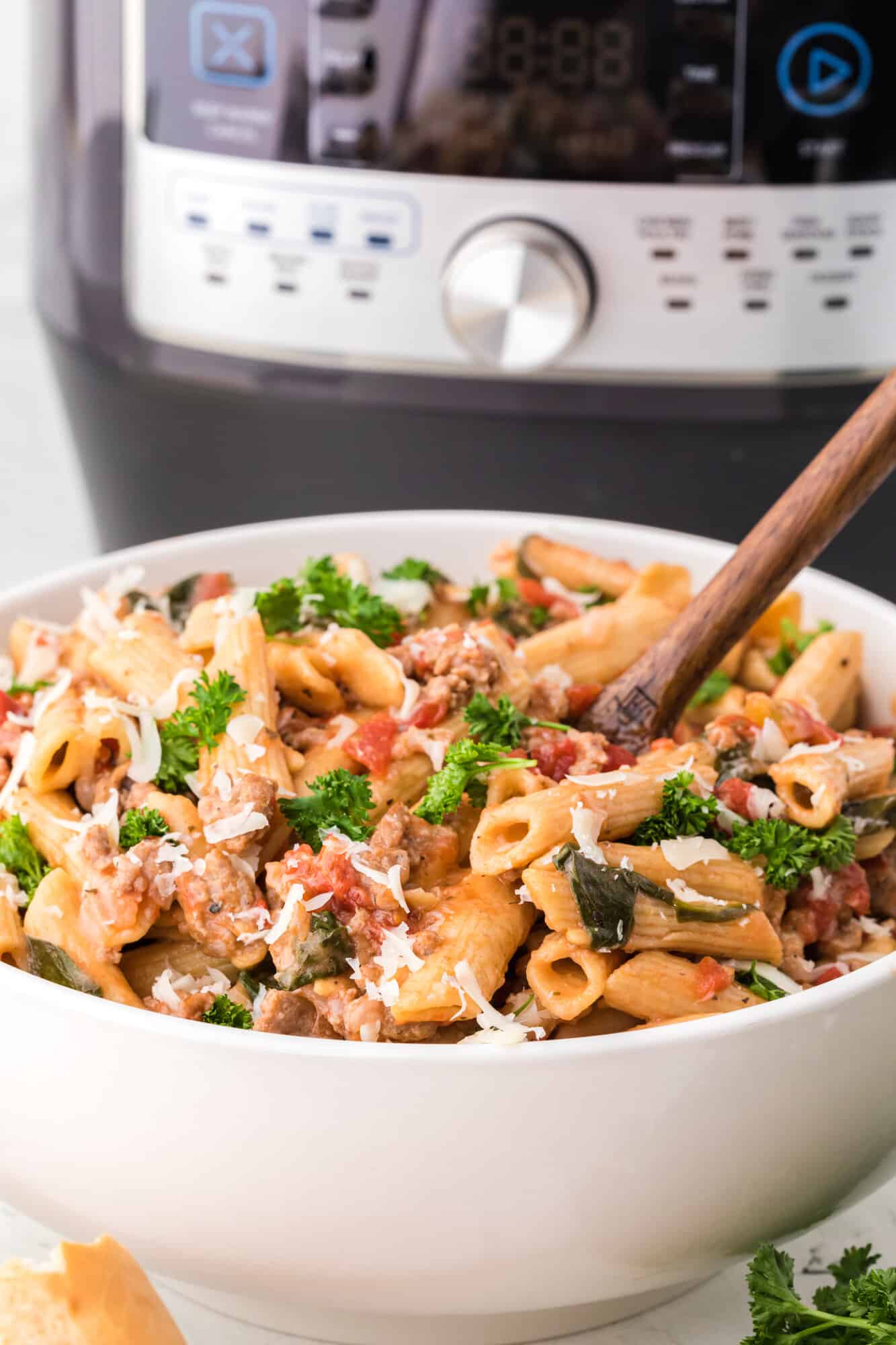 Pasta with tomatoes and spinach in front of an instant pot.