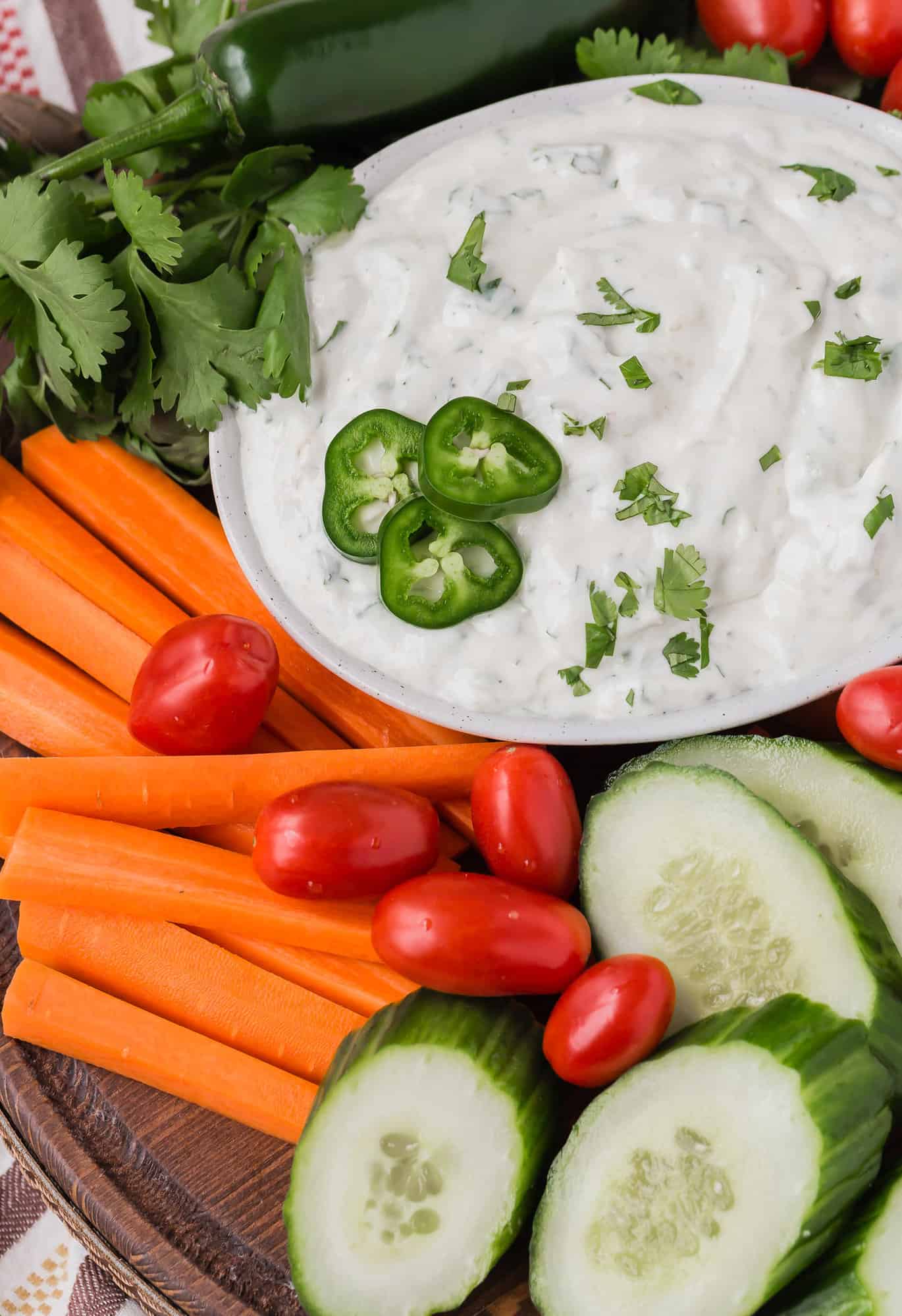Ranch dip topped with jalapeno, surrounded by vegetables.