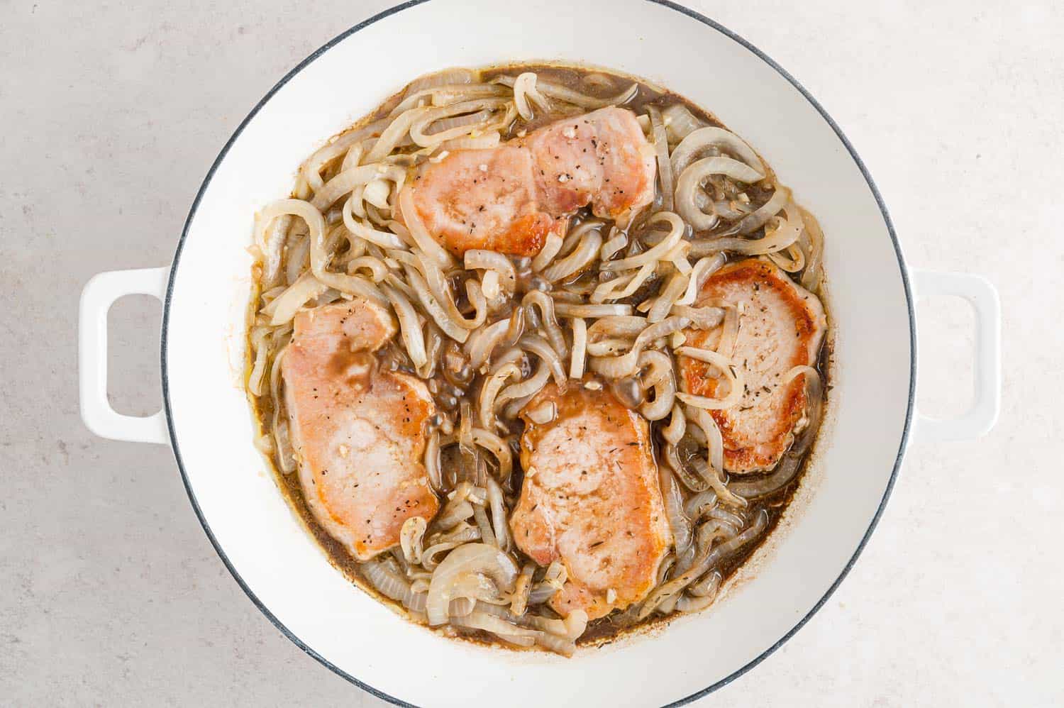 Pork chops and onions in a pan.