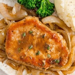 Pork chop on a plate with caramelized onions.