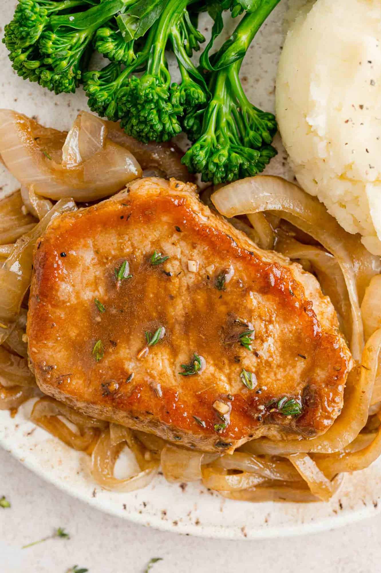 Pork chop on a plate with caramelized onions.