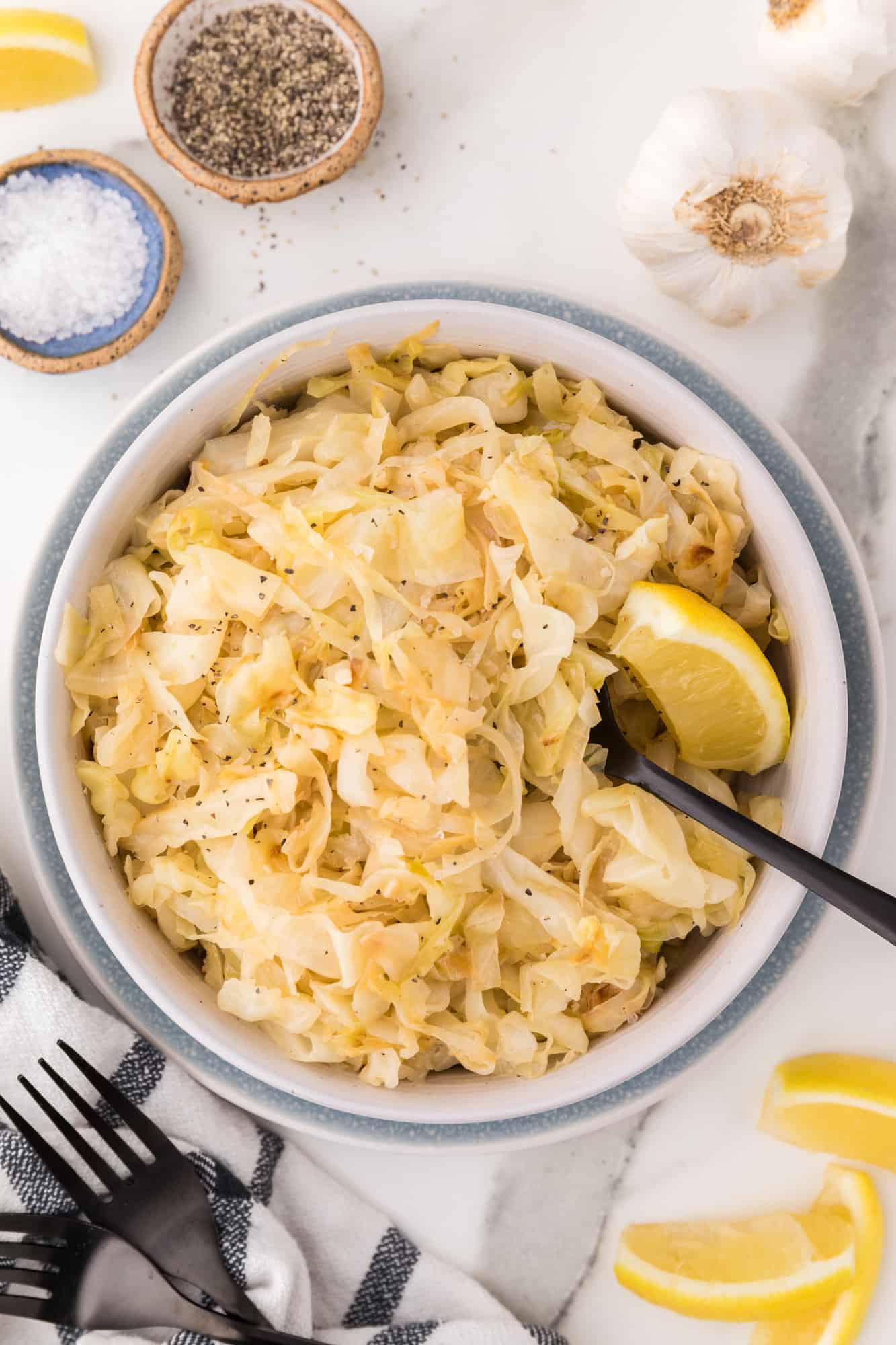 Sautéed cabbage in a large bowl with lemon wedges.