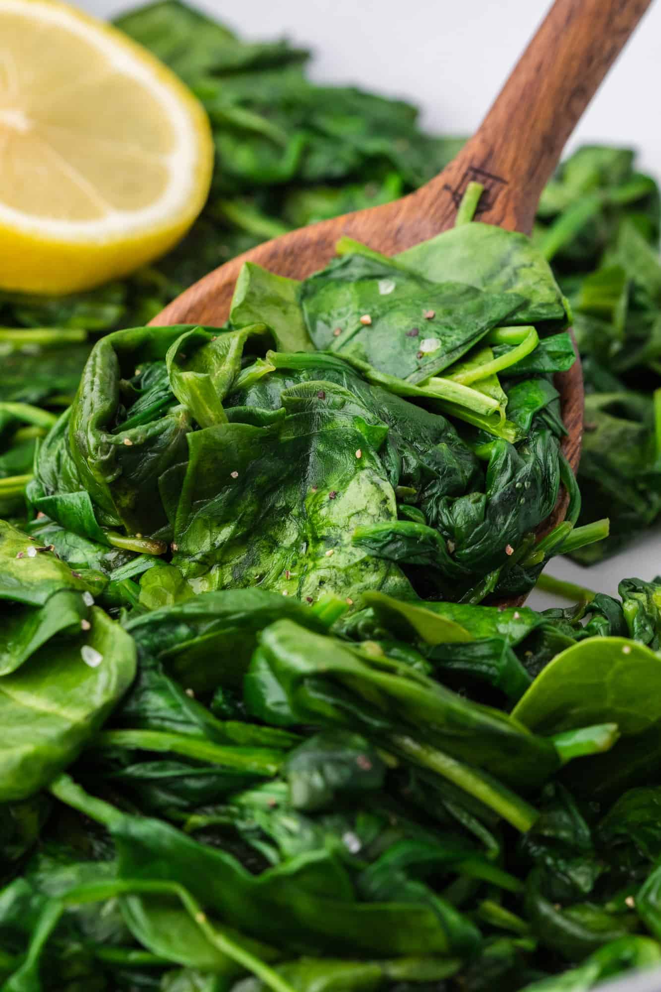 Sautéed spinach and a large wooden spoon.