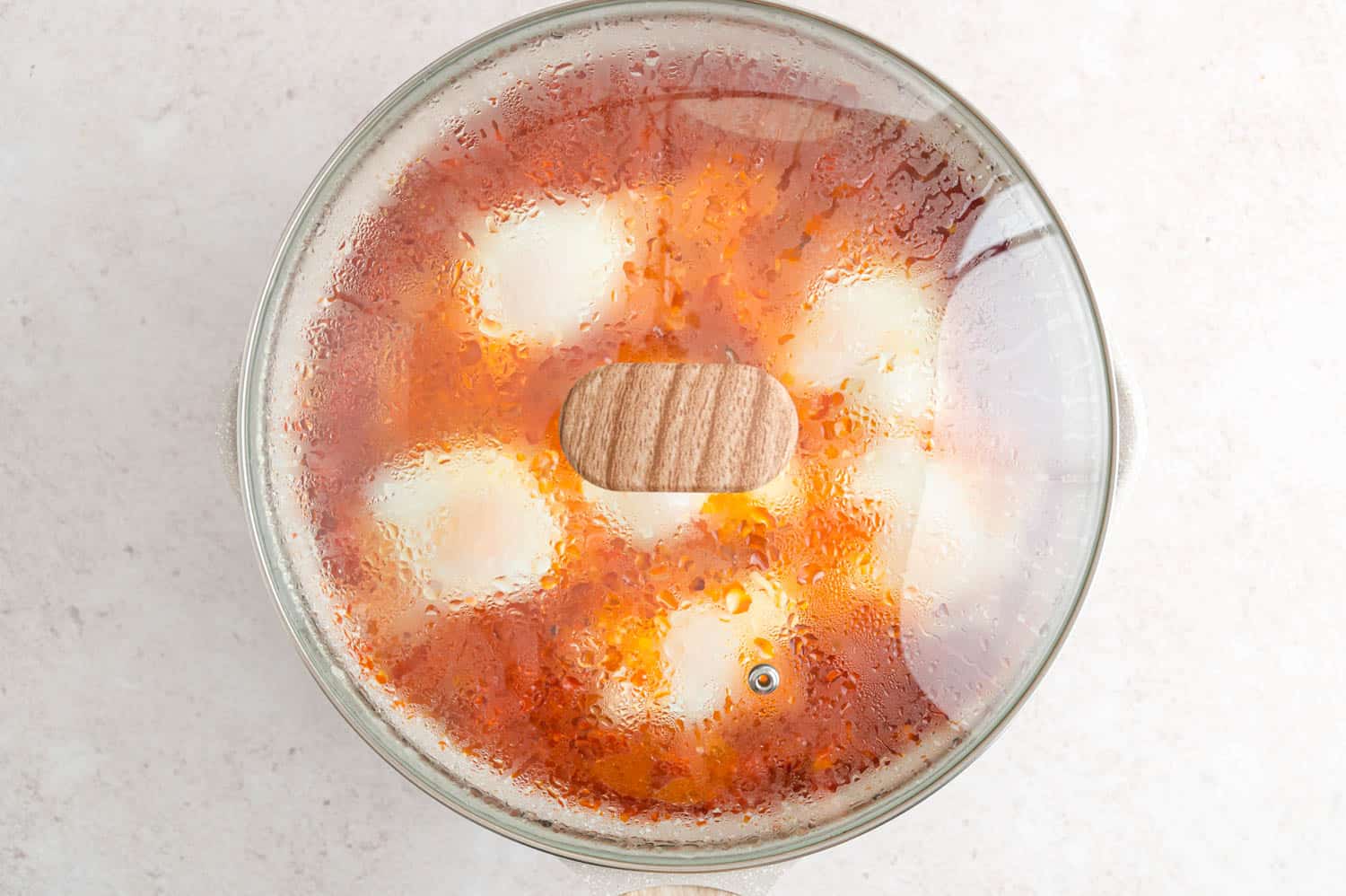 Covered pan of shakshuka showing egg cooking step.