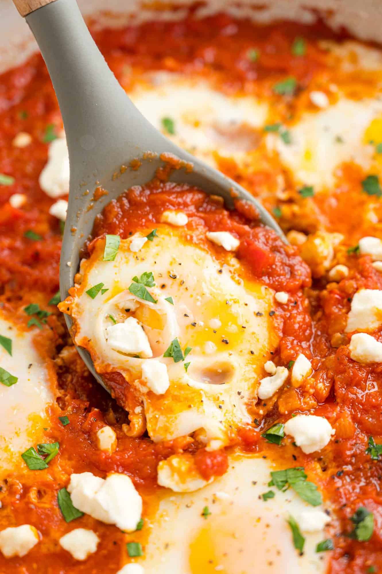 Egg being scooped from shakshuka.