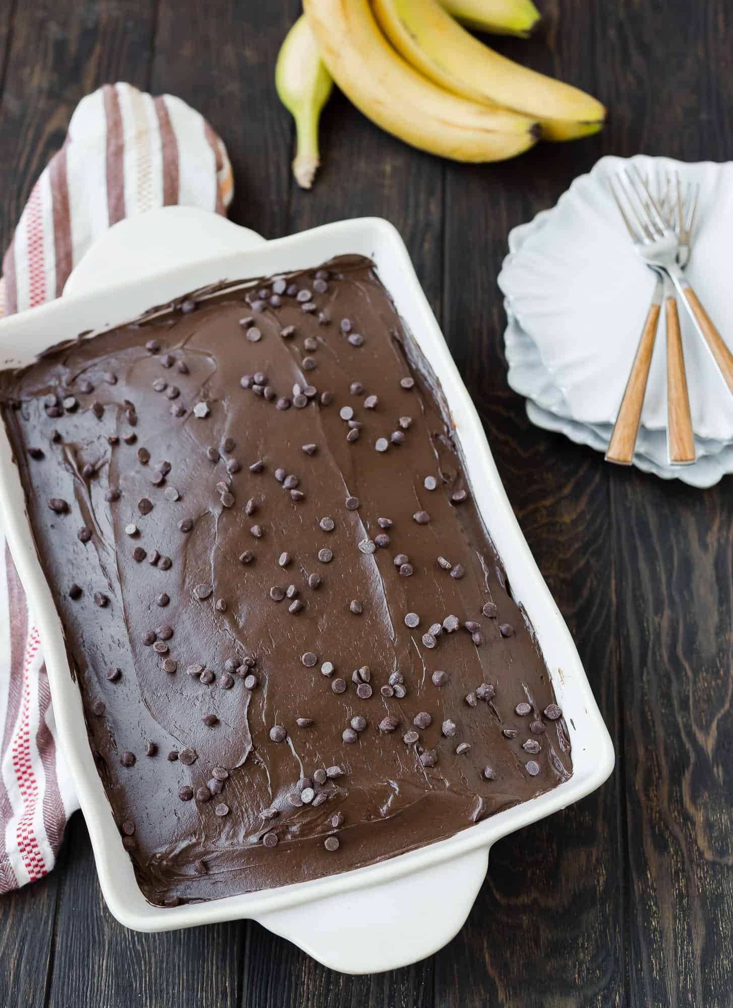 Cake with chocolate frosting in white pan.