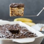 Banana cake with chocolate frosting being scooped out of pan.