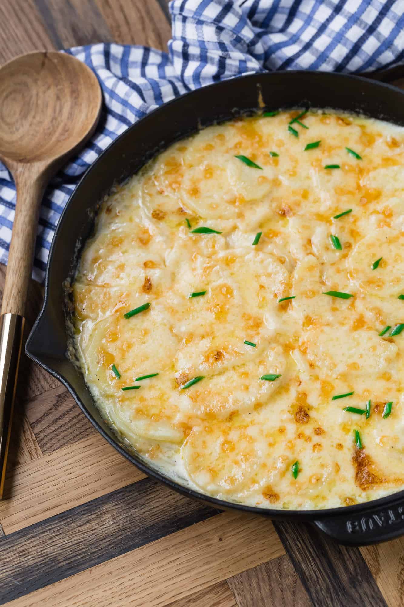 Black skillet filled with cheesy potatoes.