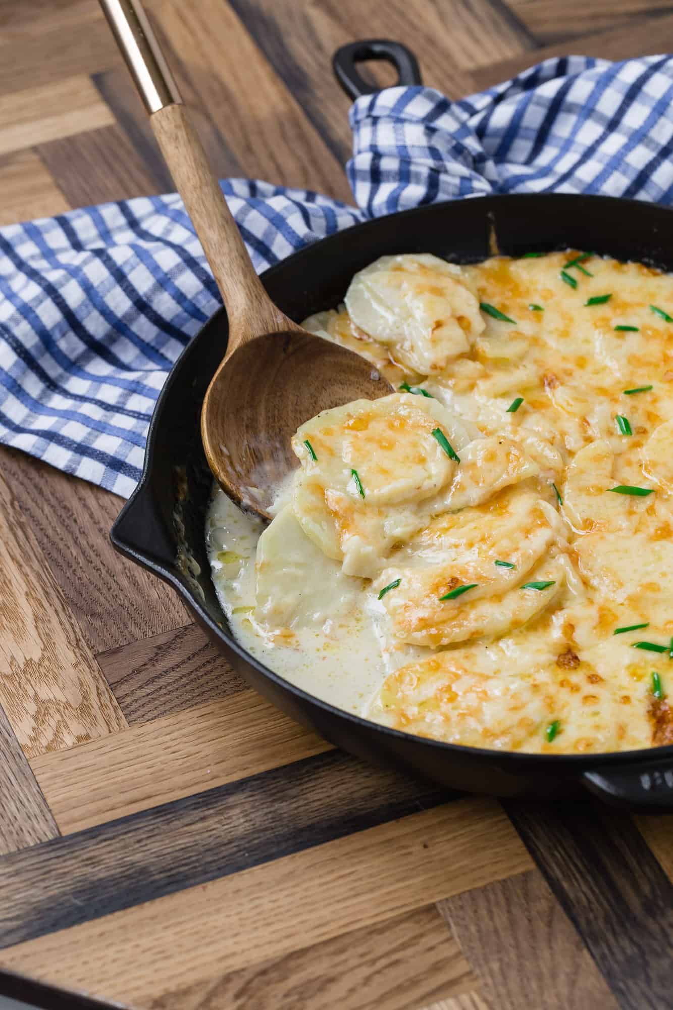 Creamy cheesy potatoes in a black skillet.