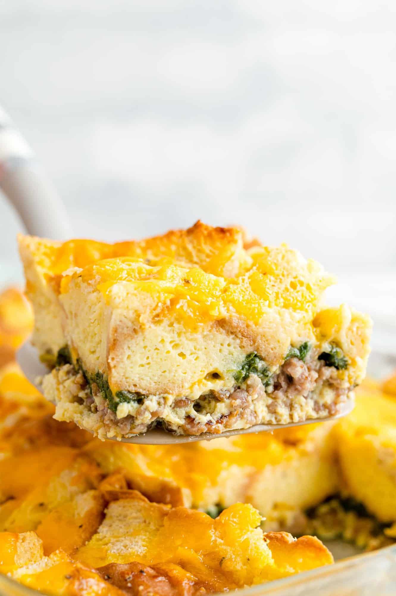 Square of breakfast casserole being scooped out of a pan.