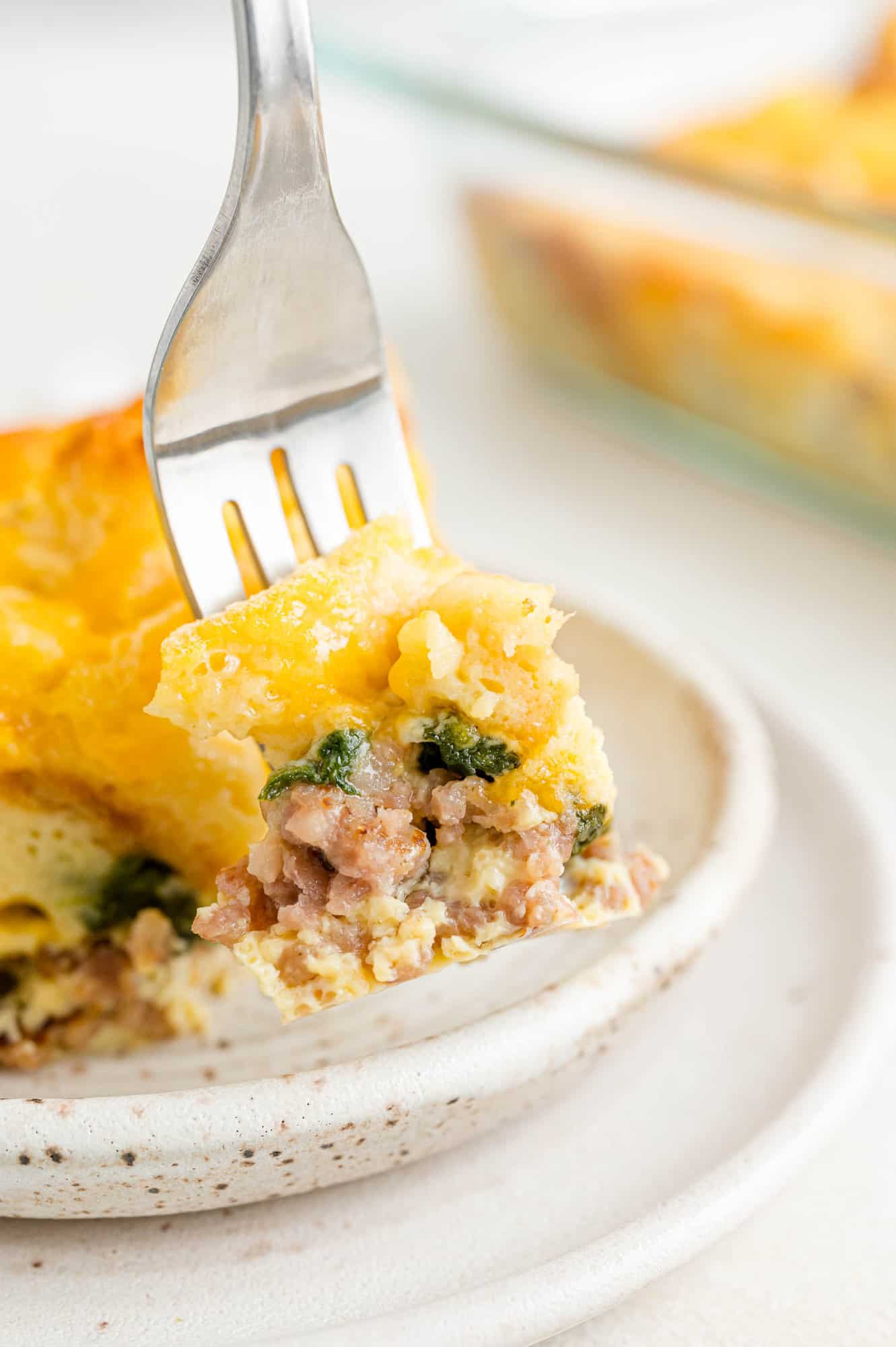 Fork cutting into a square of breakfast casserole.
