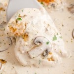 A spatula lifts a piece of chicken from a skillet of creamy chicken marsala.