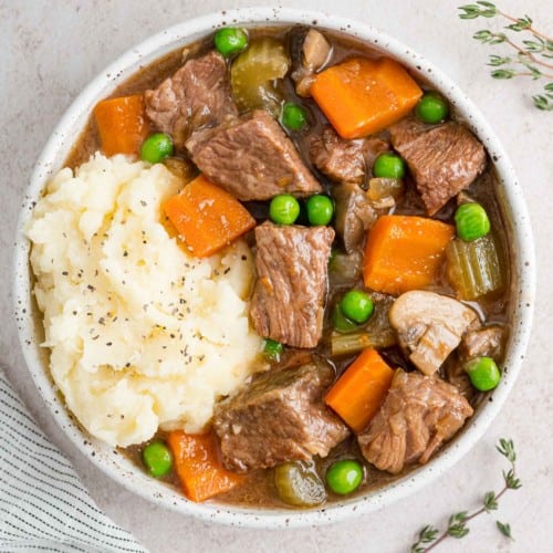 Slow cooker beef marsala stew in a white bowl with potatoes.