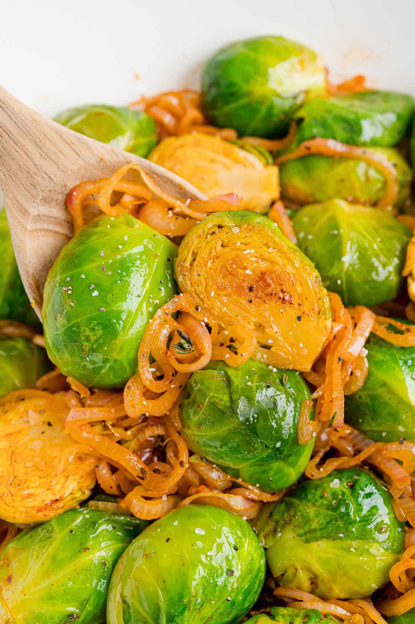 Smoky Brussels sprouts with shallots on a wooden spoon.