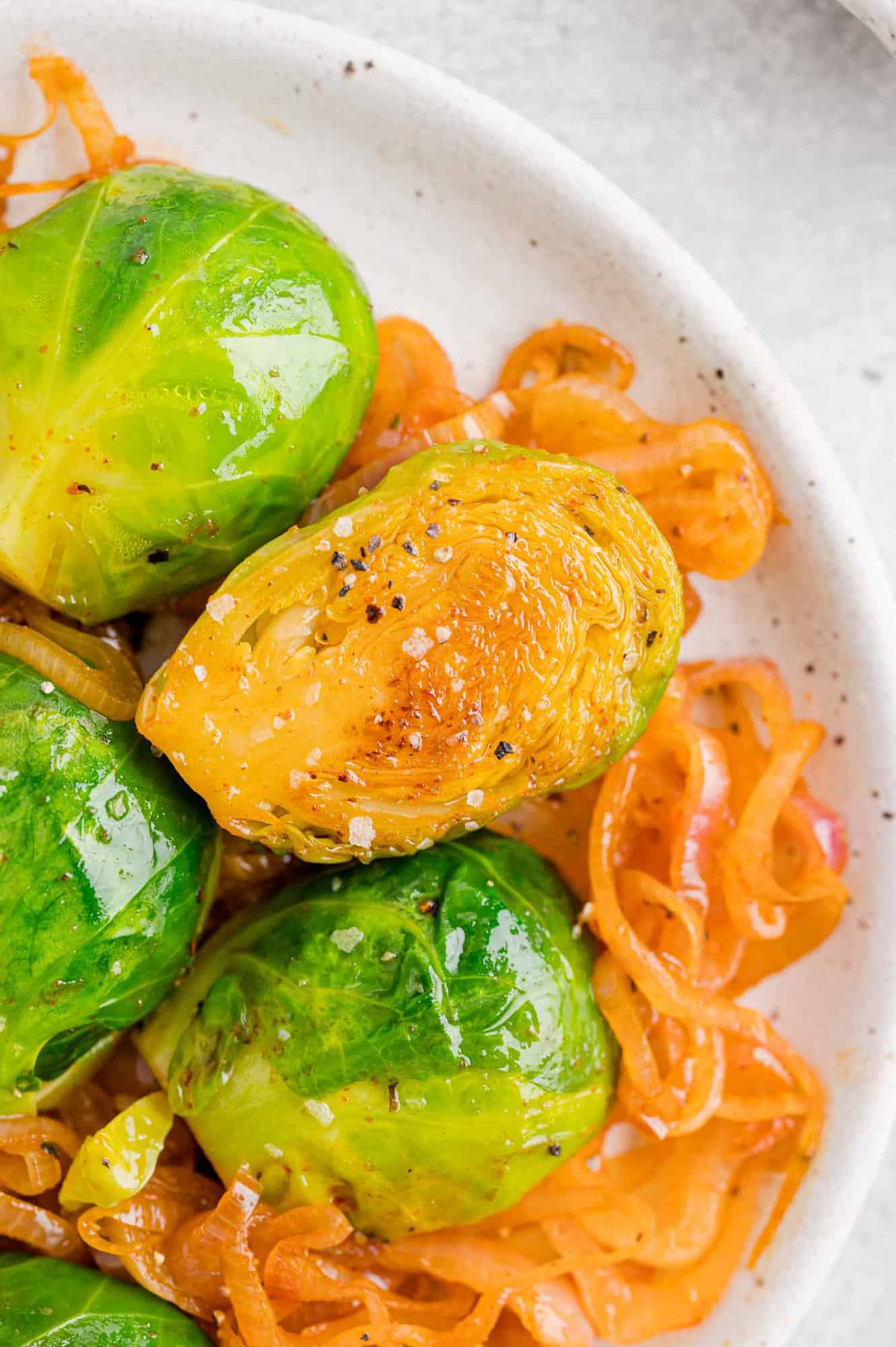 Halved cooked Brussels sprouts on top of sautéed shallots.