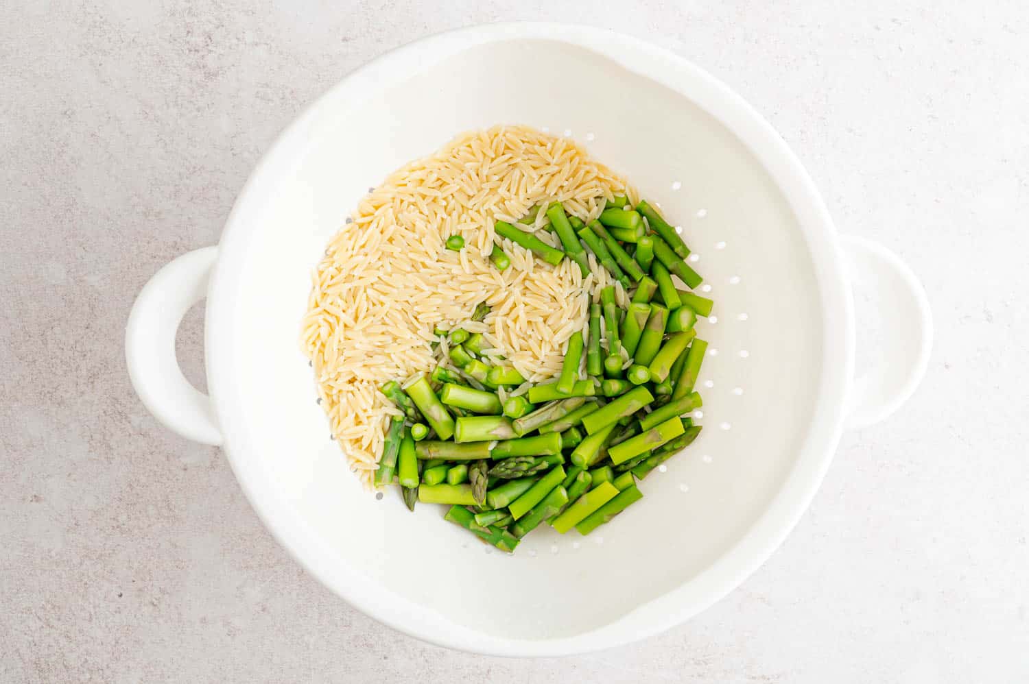 Orzo and asparagus in colander.