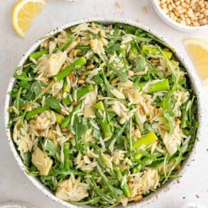 Spring orzo salad with individual ingredients surrounding bowl.