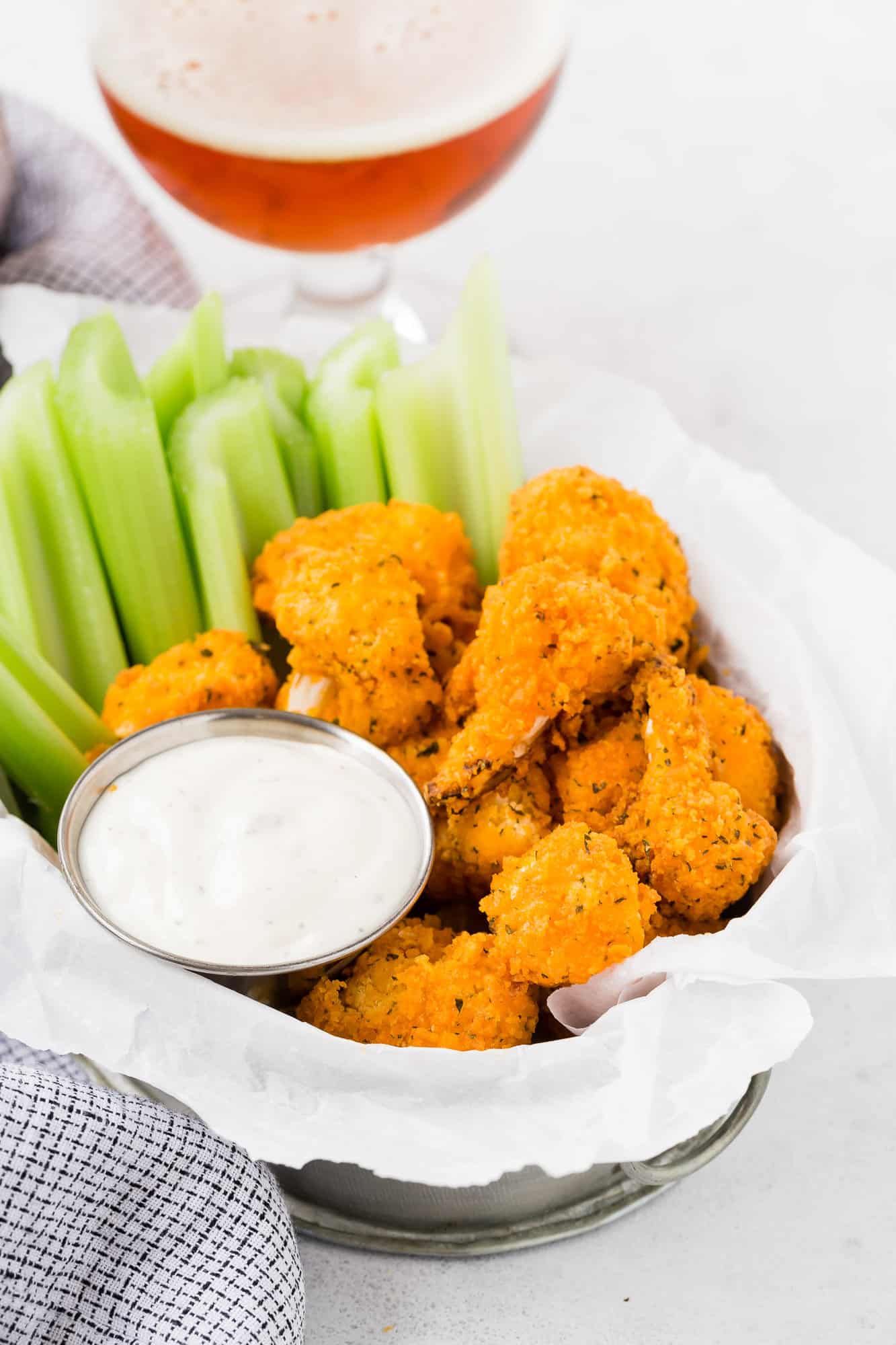 Breaded buffalo cauliflower in a basket with celery.