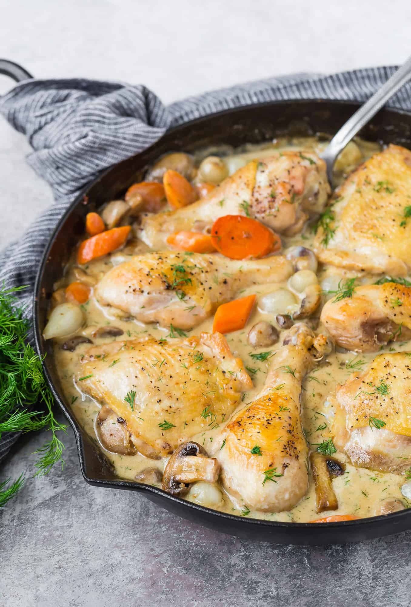 Chicken and vegetables in a black skillet.