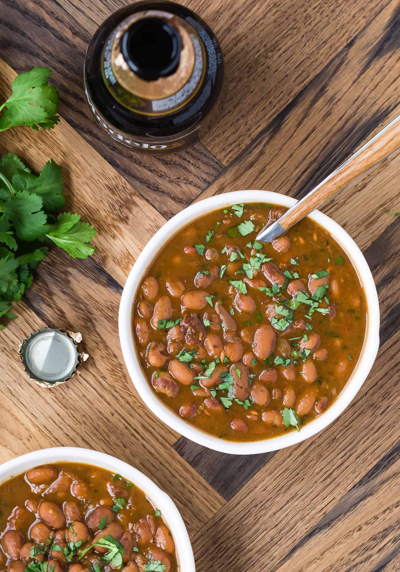 Drunken beans in a white bowl with a spoon. 