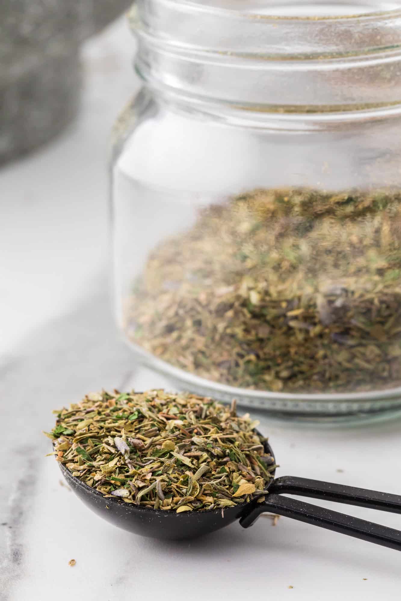 Herb mixture on a small spoon, jar in background.
