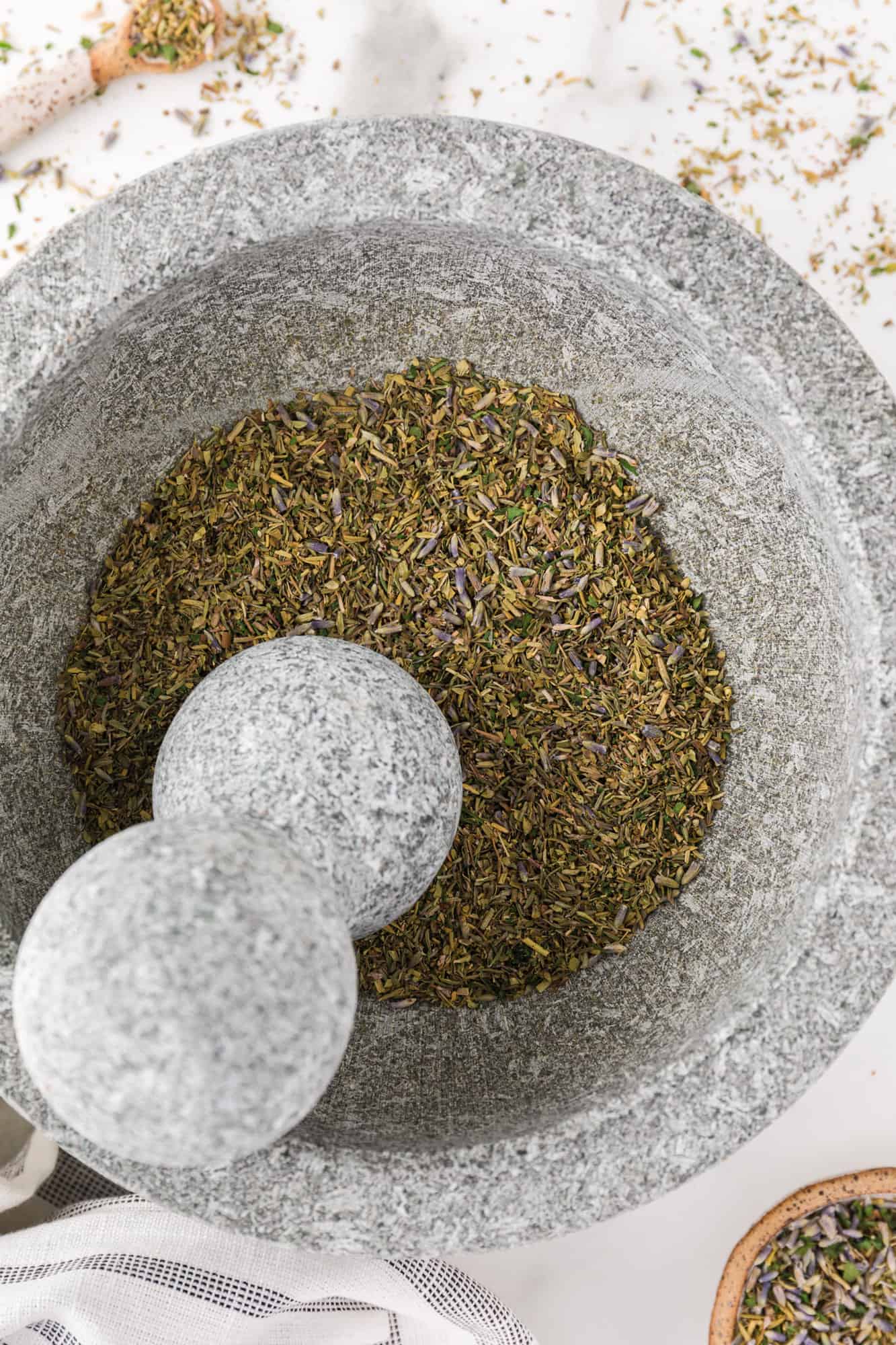 Herbs being ground in a mortar and pestle.