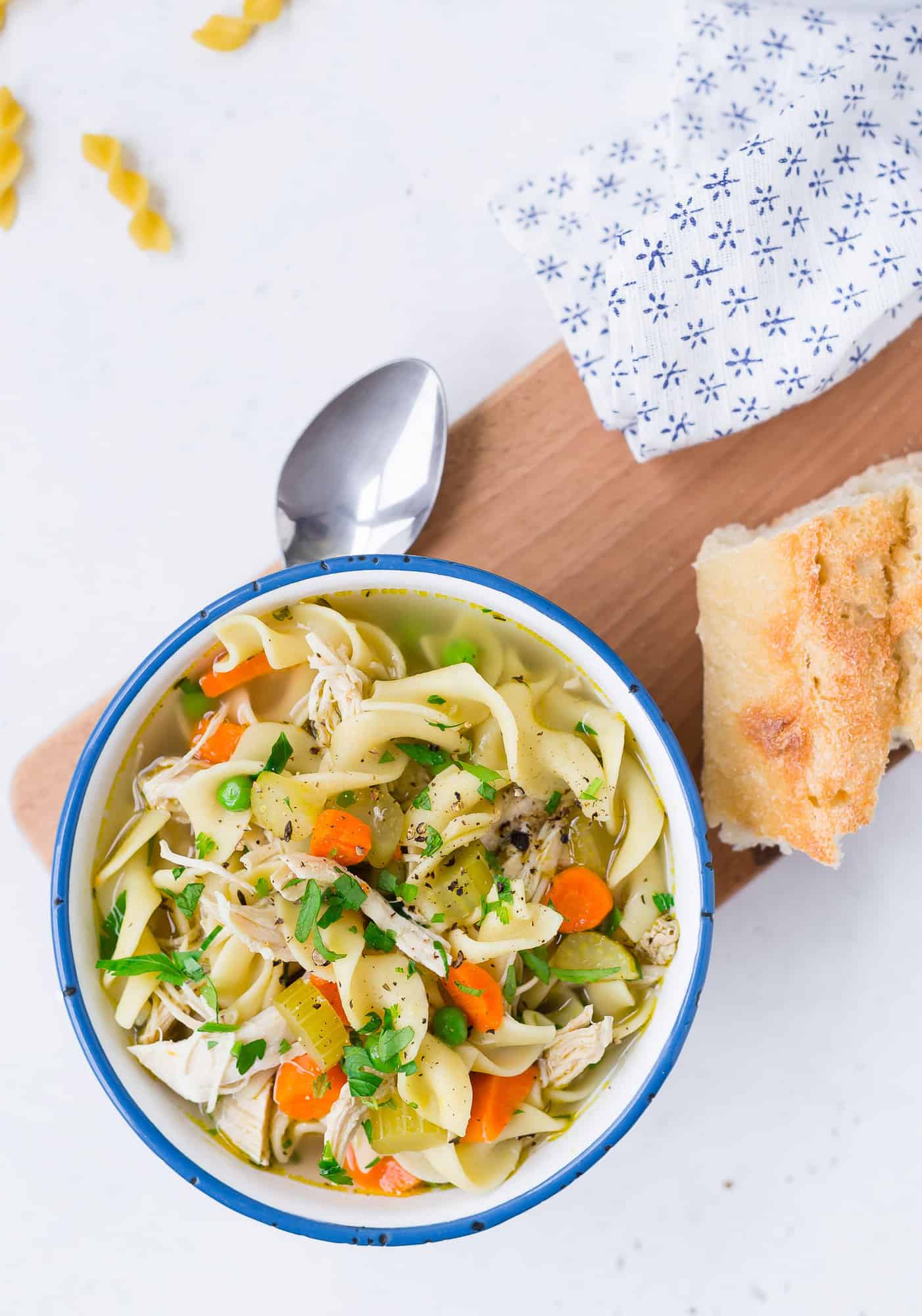 Chicken noodle soup in a blue and white bowl.